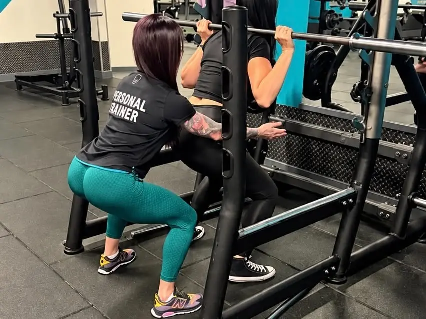 Sylwia spotting a client during a barbell squat